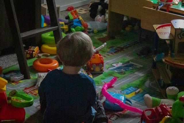How to declutter a child's room - kid sitting in the clutter of toys